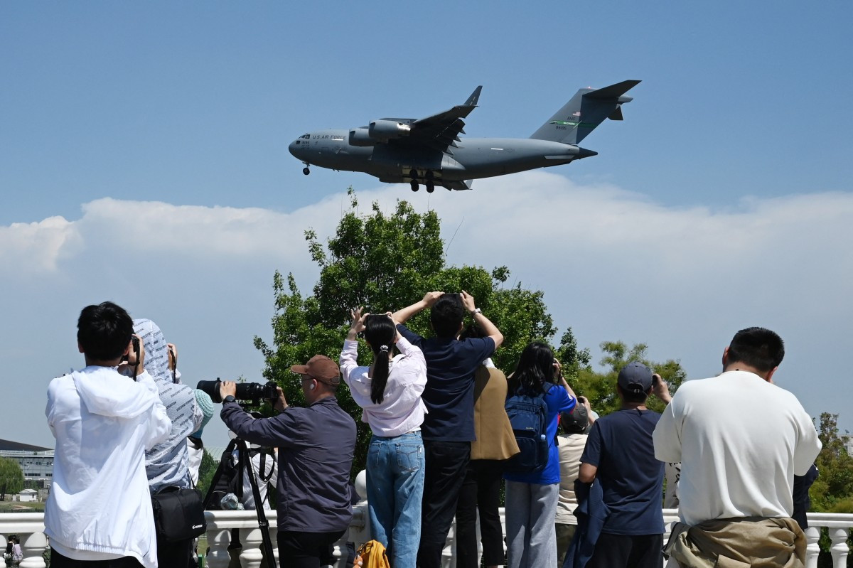 People record footage as a US Air Force C-17 Globemaster III lands at Beijing Capital Airport in Beijing on May 11, 2026, ahead of a visit by US President Donald Trump. President Trump will visit China from May 13 to 15, with the US leader expected to discuss Iran and trade with his Chinese counterpart.