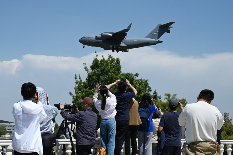 People record footage as a US Air Force C-17 Globemaster III lands at Beijing Capital Airport in Beijing on May 11, 2026, ahead of a visit by US President Donald Trump. President Trump will visit China from May 13 to 15, with the US leader expected to discuss Iran and trade with his Chinese counterpart.