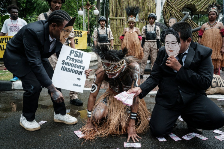 Members of Greenpeace Indonesia and Papuan youths stage a protest featuring theatrical performances against a controversial government-run sugarcane plantation plan in Merauke, Papua, outside the Office of the Coordinating  Economy Minister in Jakarta on Dec. 18, 2025. 