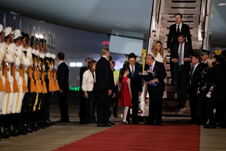 US President Donald Trump receives flowers, next to Chinese Vice President Han Zheng, Elon Musk, Eric Trump and his wife Lara, during an arrival ceremony at Beijing Capital International Airport in China on May 13, 2026. 
