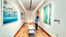 Blue stillness: A visitor lingers in a space filled with a serene, almost idyllic atmosphere from oversized photographs of icy glaciers and turquoise seas by Diane Tuft on April 23, 2026, during the opening of Unbound: Resonating Light, a joint exhibition featuring the works of Tuft and Allyson Jeong at NODE by ISA Art and Design in Kebayoran Baru, South Jakarta.