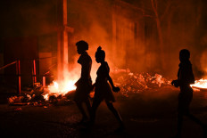 People walk past a fire set by demonstrators during a protest against the lack of energy and blackouts in the Lawton neighborhood in Havana on May 14, 2026.