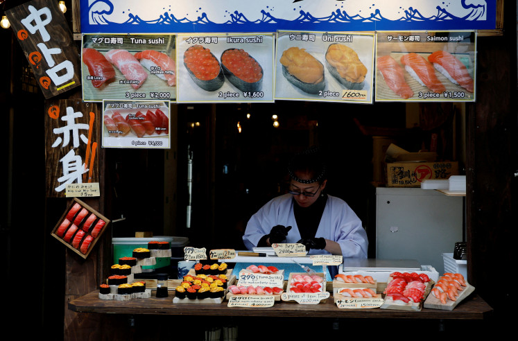A vendor works at a shop selling sushi rolls at Tsukiji Outer Market in Tokyo on Feb. 16, 2026.