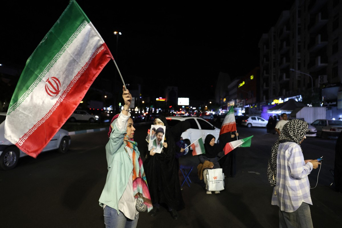 Women hold Iran's national flags and photos of country's supreme leader Ayatollah Mojtaba Khamenei and his predecessor and late father Ayatollah Ali Khamenei during an anti-US and Israel protest at the Hafte Tir Square in Tehran on May 17, 2026.