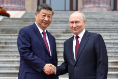 In this pool photograph distributed by the Russian state agency Sputnik, Russia's President Vladimir Putin (right) and China's President Xi Jinping shake hands during a welcome ceremony at the Great Hall of the People in Beijing on May 20, 2026.