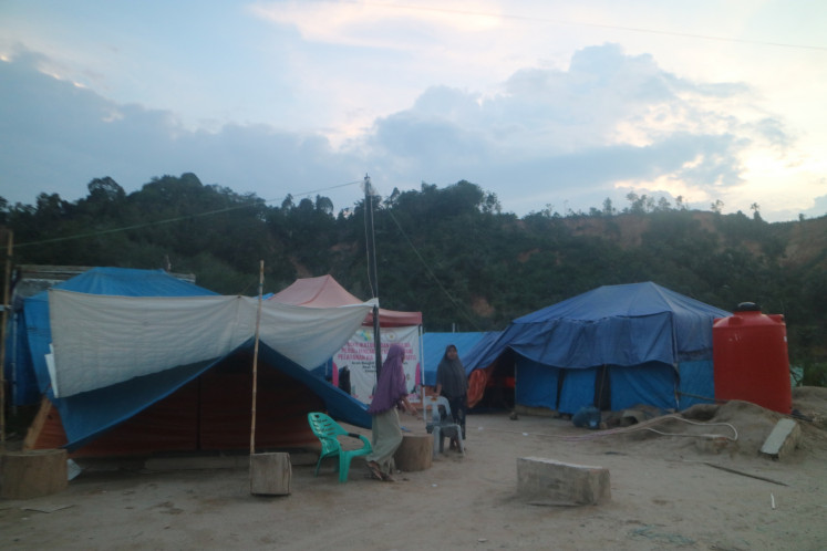 Two women hang out near emergency tents in Lubuk Sidup village, Aceh Tamiang regency, Aceh on May 11, 2026, where dozens of survivors of the deadly cyclone-induced flooding and landslides in northern Sumatra continue to live.