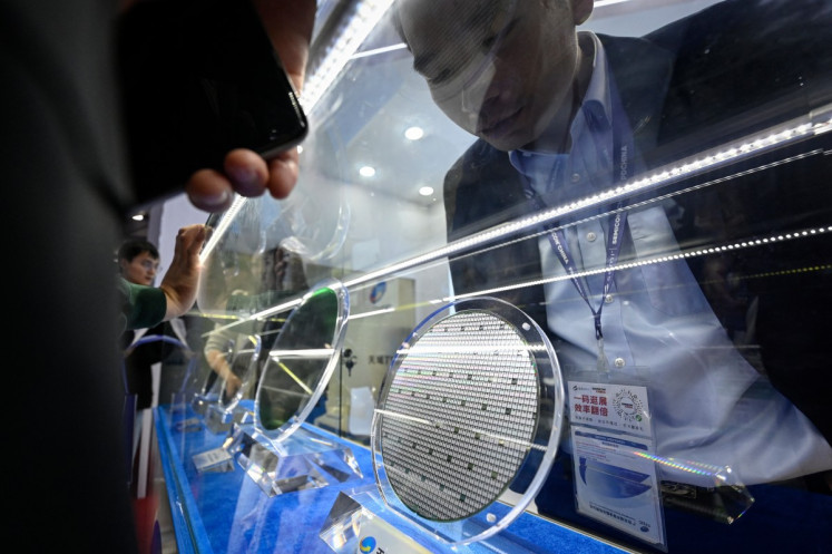 An attendant looks at a semiconductor wafer on March 25 at the SEMICON China 2026 trade fair in Shanghai.