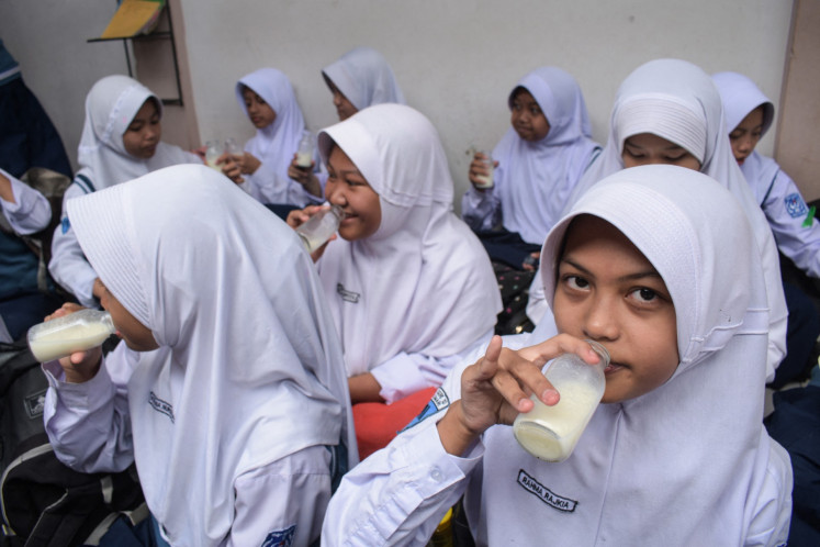 Students drink milk as they eat lunch on Jan 6, 2025, the first day of the free nutritious meal program, at SMPN 12 Cimahi state junior high school in Cimahi, West Java.