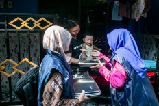 Volunteers give a meal package under the free nutritious meal program to a mother and her baby  on May 5, 2026, in Surakarta, Central Java.