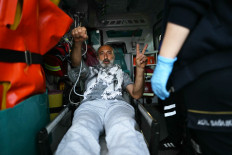 A member of the Global Sumud Flotilla headed for Gaza and arrested and deported by Israel gestures the V-sign and a raised fist as he is loaded into an ambulance following the group's arrival at Istanbul Airport on May 21, 2026. The first of hundreds of Gaza flotilla activists began arriving at Istanbul airport on May 21 after being arrested then deported from Israel.