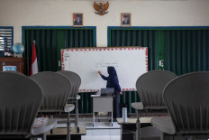 An elementary school teacher teaches her pupils online due to worsening air quality caused by forest fires in Palembang, South Sumatra, on Oct. 5, 2023.