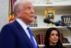 Then-incoming director of National Intelligence Tulsi Gabbard (right) looks at United States President Donald Trump during her swearing in ceremony as DNI in the Oval Office at the White House in Washington, D.C., on Feb. 12, 2025.