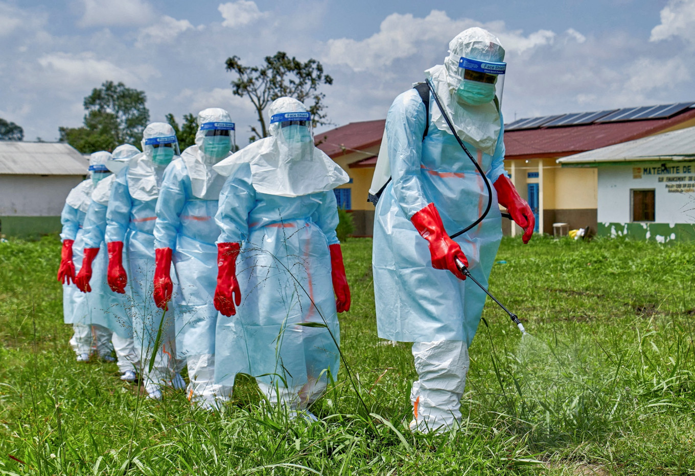 Red Cross workers walk in a formation as they disinfect Rwampara general hospital in Rwampara outside Bunia, Ituri province, Democratic Republic of Congo, on May 21, 2026, before handling the body of a person who died of Ebola, as aid agencies intensify efforts to contain a new Ebola outbreak involving the Bundibugyo strain.