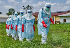 Red Cross workers walk in a formation as they disinfect Rwampara general hospital in Rwampara outside Bunia, Ituri province, Democratic Republic of Congo, on May 21, 2026, before handling the body of a person who died of Ebola, as aid agencies intensify efforts to contain a new Ebola outbreak involving the Bundibugyo strain.