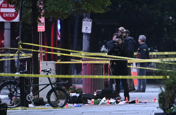 A forensic investigator takes photos behind a police tape blocking off a crime scene with evidence markers seen on a sidewalk on 17th and Pennsylvania Ave near the White House in Washington, DC, on May 23, 2026. Police and security forces swarmed the area around the White House on the evening of May 23 after reports of shots fired, AFP journalists said. US President Donald Trump was at the White House at the time as he worked to negotiate a deal with Iran.