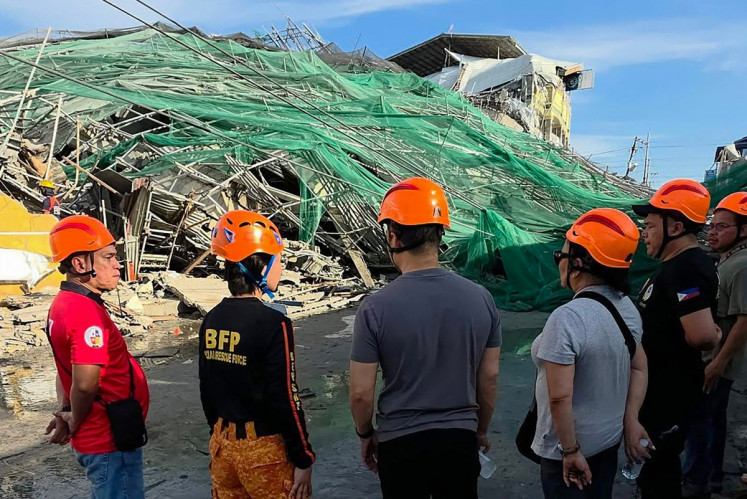 This handout photo taken and released on May 24, 2026 via the Facebook page of the Angeles City Public Information Office shows rescuers standing next to a collapsed building in Angeles City in Pampanga province. Nineteen people are feared trapped after a building under construction near Manila collapsed early on May 24, a local government official said.