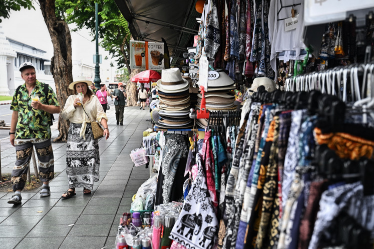 Tourists walk past souvenir shops outside the Grand Palace in Bangkok on May 20, 2026.