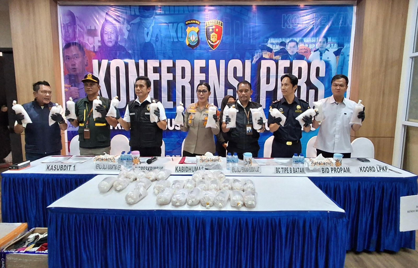 Riau Islands Police' Special Crimes Investigation (Reskrimsus) director Sr. Comr. Silvester Mangombo Marusha Simamora (third left) and chief spokeswoman Sr. Comr. Nona Pricillia Ohei (center) hold bags containing lobster larvae together with representatives from related agencies during a press conference in Batam, Riau Islands, on May 20, 2026. 