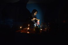 A vendor prepares drinks for customers in the dim light of candles on May 23, 2026, during a power outage in Nagari Kasang, Padang Pariaman regency, West Sumatra.