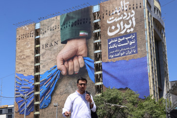 Echoes of Persian power: A man crosses a street past a billboard on the facade of a building depicting the Strait of Hormuz with a caption in Persian reading &ldquo;Forever in Iran&rsquo;s Hand&rdquo;, on Monday, May 25, 2026, at Vanak Square in Tehran.