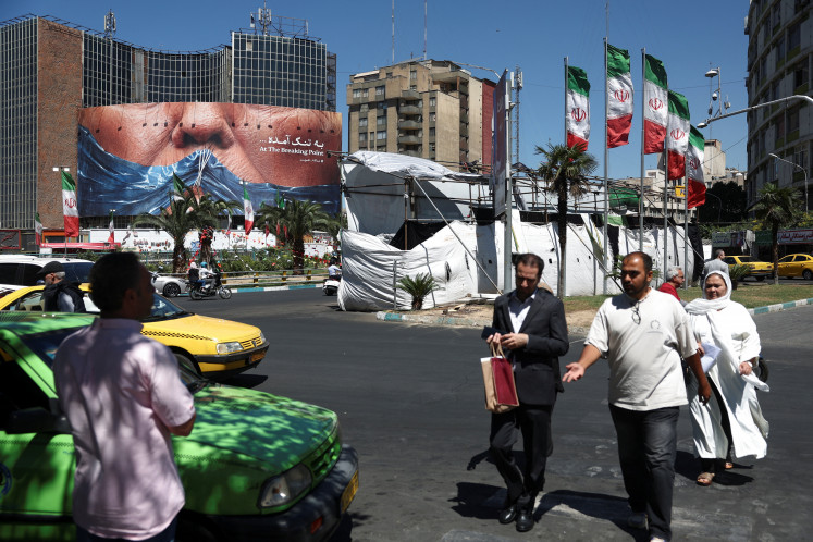 People walk past an anti-US billboard depicting US President Donald Trump and the Strait of Hormuz, in Tehran, on May 26, 2026.