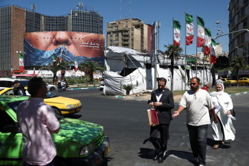 People walk past an anti-US billboard depicting US President Donald Trump and the Strait of Hormuz, in Tehran, on May 26, 2026.