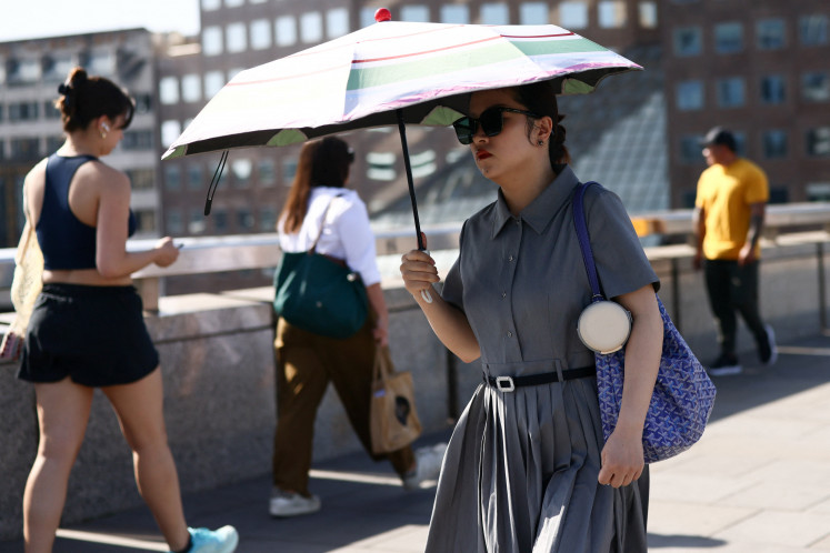 A woman shields herself from the sun as she crosses London Bridge during a heatwave, after the UK recorded its hottest May bank holiday ever, in London, Britain, May 26, 2026.