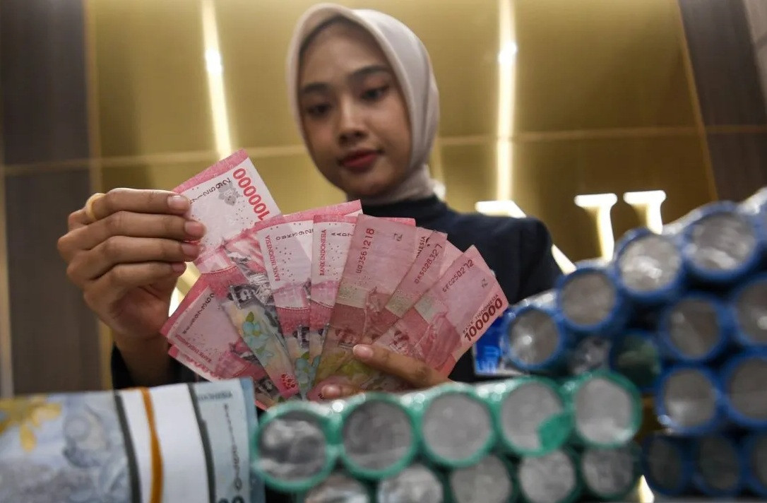 A teller counts rupiah banknotes on Oct. 27, 2025, at the BNI Pasar Baru branch in Jakarta. Bank Indonesia has opted to hold its benchmark BI rate at 4.75 percent, the Deposit Facility rate at 3.75 percent and the Lending Facility rate at 5.50 percent to maintain rupiah exchange rate stability.