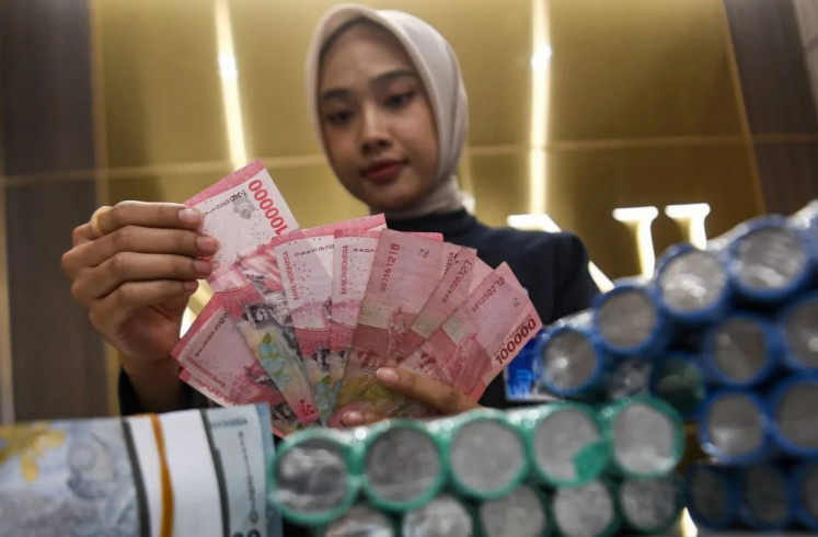 A teller counts rupiah banknotes on Oct. 27, 2025, at the BNI Pasar Baru branch in Jakarta. Bank Indonesia has opted to hold its benchmark BI rate at 4.75 percent, the Deposit Facility rate at 3.75 percent and the Lending Facility rate at 5.50 percent to maintain rupiah exchange rate stability.