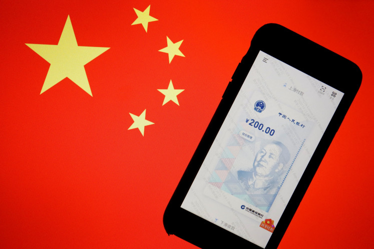 China's official app for digital yuan is seen on a mobile phone placed in front of an image of the Chinese flag, in this illustration picture taken on Oct. 16, 2020.
