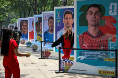 A woman poses with the image of Portuguese footballer Cristiano Ronaldo during an exhibition of the Panini World Cup Album at the Reforma Avenue in Mexico City on May 11, 2026, one month ahead of the opening match of the FIFA World Cup 2026 between Mexico and South Africa. 