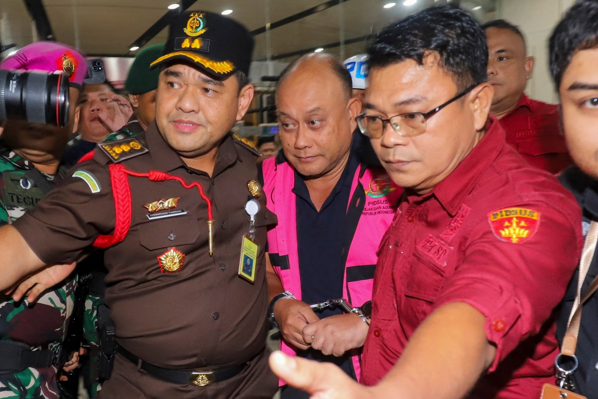 Dadan Hindayana (center), the former head of an agency overseeing Indonesia's free meals program, is escorted by officers from the Attorney General's Office and Indonesian military personnel as he leaves the AGO building in Jakarta on June 3, 2026, following questioning over alleged misappropriation in the implementation of the program. Indonesian authorities on June 3 arrested the head of the body responsible for President Prabowo Subianto's signature free school meals program, a day after he was removed on concerns including food quality.