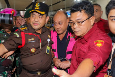 Dadan Hindayana (center), the former head of an agency overseeing Indonesia's free meals program, is escorted by officers from the Attorney General's Office and Indonesian military personnel as he leaves the AGO building in Jakarta on June 3, 2026, following questioning over alleged misappropriation in the implementation of the program. Indonesian authorities on June 3 arrested the head of the body responsible for President Prabowo Subianto's signature free school meals program, a day after he was removed on concerns including food quality.