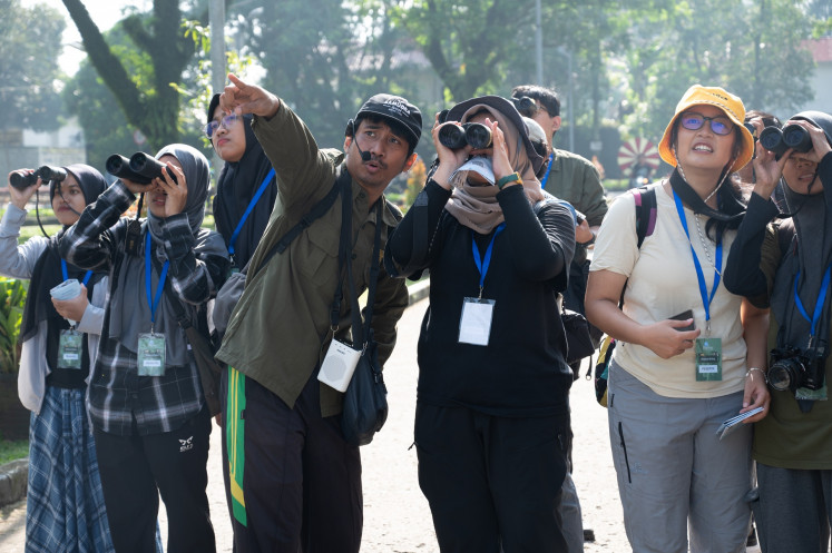 Peeking birds: A guide points while participants look for a bird during a birdwatching activity held by conservation group Burung Indonesia at the Bogor Agricultural University (IPB) in Bogor, West Java on Sept. 20, 2025. Weekend Birding is one of regular programs held by the group to engage the public to be involved in citizen science by observing and documenting various species of birds.