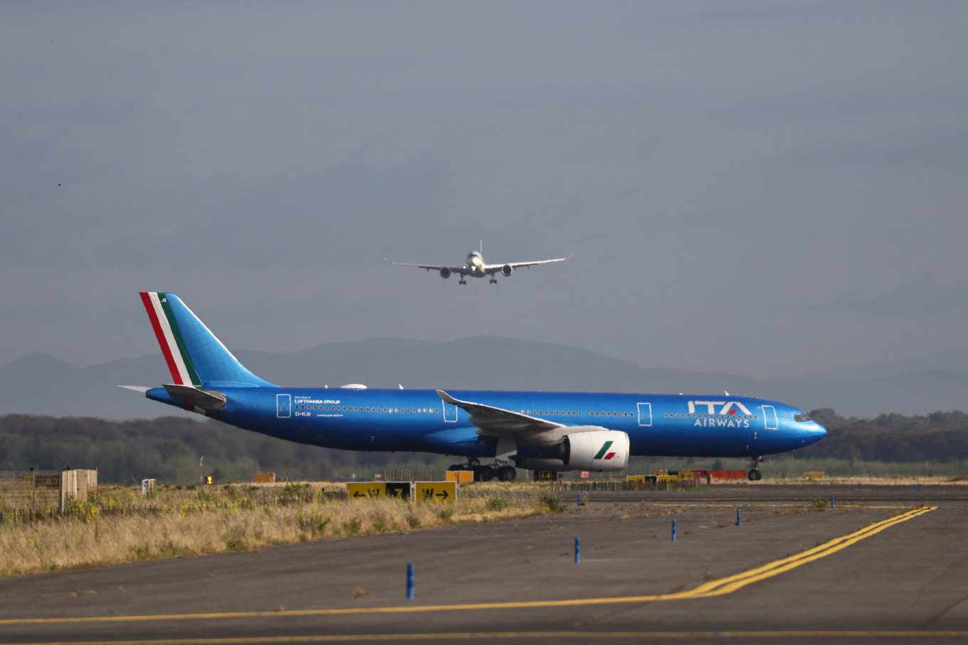 An ITA Airways aircraft stands on the tarmac as another aircraft approaches Rome's Fiumicino airport, as European airlines monitor higher jet fuel costs and supply concerns linked to tensions in the Middle East, in Fiumicino, Italy, on June 6, 2026.