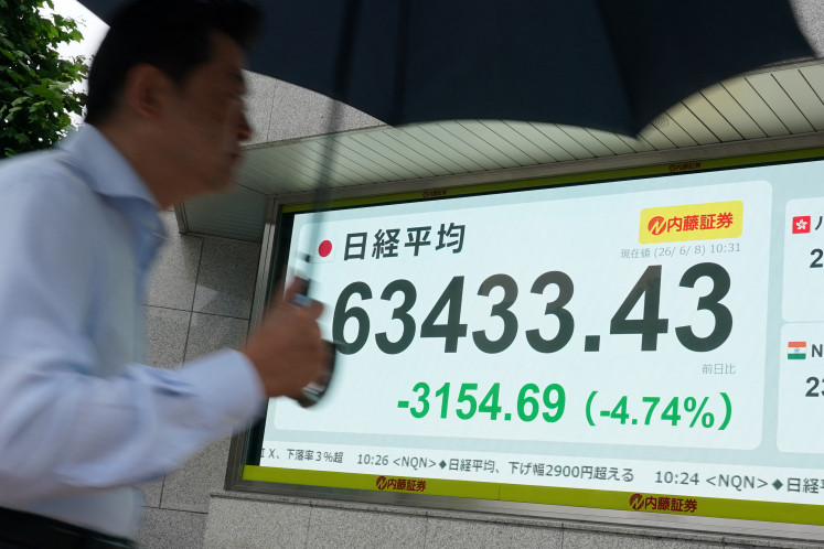 A man walks past an electronic quotation board displaying the Nikkei Stock Average on the Tokyo Stock Exchange along a street in Tokyo on June 8, 2026.