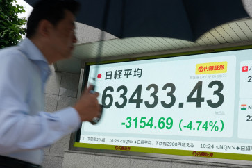 A man walks past an electronic quotation board displaying the Nikkei Stock Average on the Tokyo Stock Exchange along a street in Tokyo on June 8, 2026.