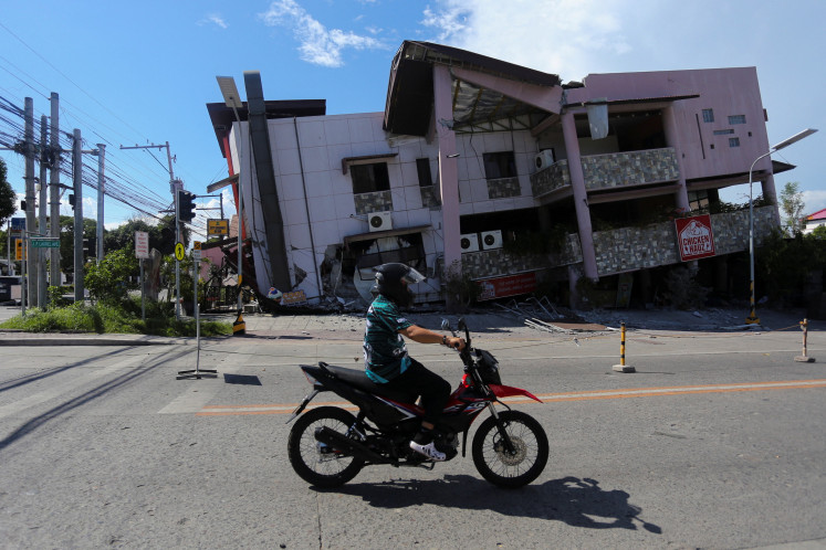 A motorcyclist rides past a damaged building following the magnitude 7.8 quake in General Santos, southern Philippines, June 8, 2026. 