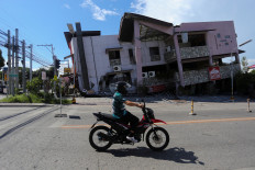 A motorcyclist rides past a damaged building following the magnitude 7.8 quake in General Santos, southern Philippines, June 8, 2026. 
