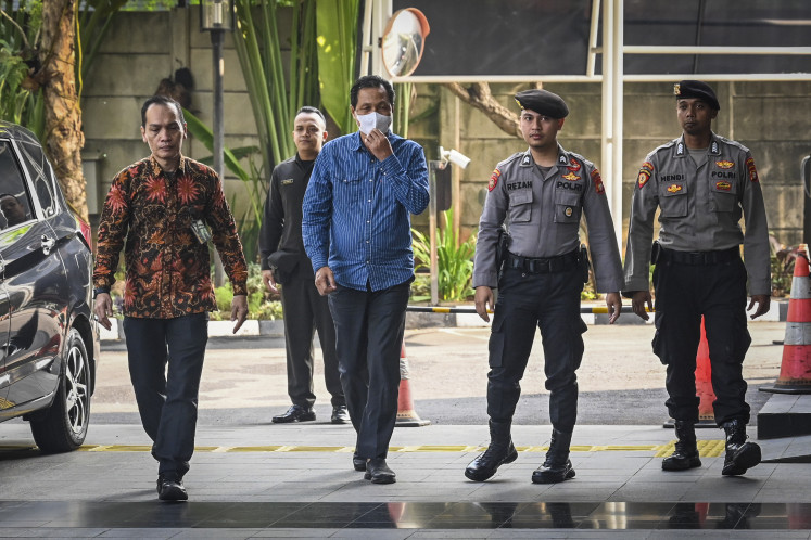 Muara Enim Regent Edison (center) is escorted by police officers on June 9 upon arriving at the Corruption Eradication Commission (KPK) headquarters in South Jakarta. Edison was apprehended in a graft raid conducted by the KPK a day prior in an alleged corruption case involving procurement of goods and services within the Muara Enim Education and Culture Agency.