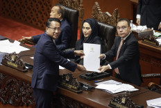 Law Minister Supratman Andi Agtas (left) hands over a document containing the government's response to the revision to the 2002 Police Law to House of Representatives Deputy Speaker Sufmi Dasco Ahmad on June 9 during a House plenary session at the Senayan Legislative Complex in Jakarta. In the session, the House passed the new law unanimously.