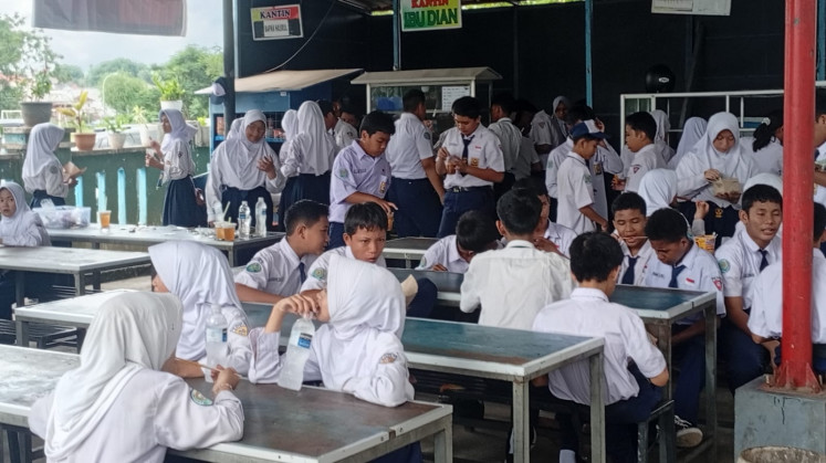 Students munch on snacks and sip bottled water or cups of tea on June 8, 2026, in the canteen at SMPN 12 Batam junior high school in Batam, the Riau Islands, after local nutrition fulfillment service units (SPPG) halted operations for the free nutritious meal program due to alleged funding stoppage by the National Nutrition Agency (BGN).