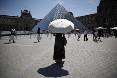 A person protects from the sun under an umbrella in front of the Louvre museum in Paris as a record-breaking early heatwave scorches a swathe of western Europe on May 28, 2026. The UK and France have reported their hottest ever May days this week as a &ldquo;heat dome&ldquo; brought sizzling temperatures more typical of midsummer to western Europe. UN climate chief Simon Stiell said the heatwave was &ldquo;a brutal reminder of the spiraling impacts of the climate crisis. &ldquo;The science is clear that human-induced climate change is making these heatwaves more frequent and extreme,&ldquo; Stiell add in a statement. 