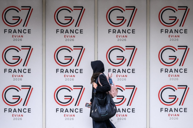 A passer-by walks past logos of the G7 summit in Evian, central-eastern France on June 10, 2026.