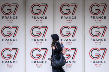 A passer-by walks past logos of the G7 summit in Evian, central-eastern France on June 10, 2026.