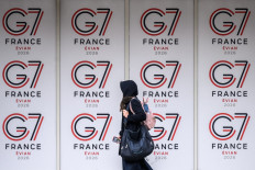 A passer-by walks past logos of the G7 summit in Evian, central-eastern France on June 10, 2026.