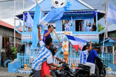 Argentina fan and fisherman Muhammad Yusuf (back, center) holds a replica of the World Cup trophy as football fans pass his house, painted in the colors of the Argentine national team, in a convoy welcoming the 2026 FIFA World Cup football tournament on the eve of its start in Polewali Mandar, West Sulawesi on June 11, 2026.