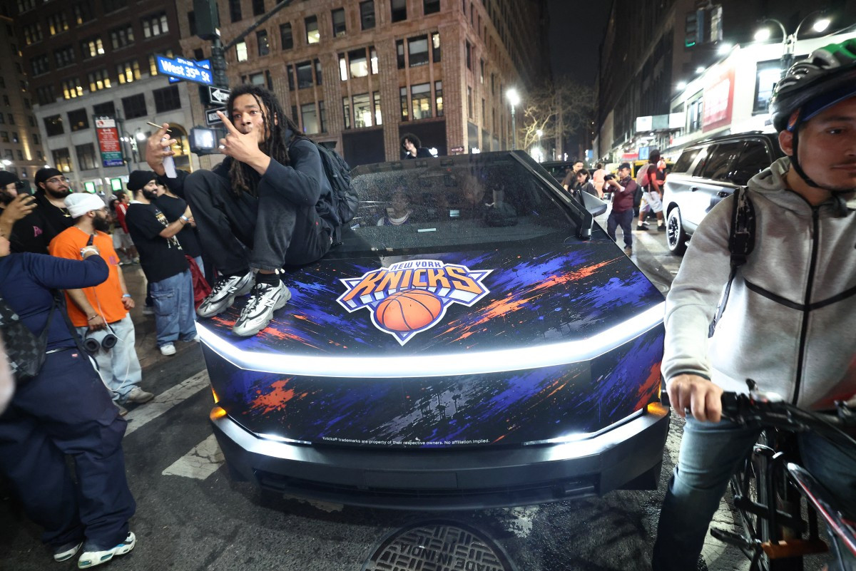 A New York Knicks fan sits on the hood of a car with Knicks stickers in New York, the United States on June 10, 2026 during game four of the NBA Finals between the San Antonio Spurs and the New York Knicks.
