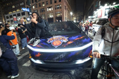 A New York Knicks fan sits on the hood of a car with Knicks stickers in New York, the United States on June 10, 2026 during game four of the NBA Finals between the San Antonio Spurs and the New York Knicks.