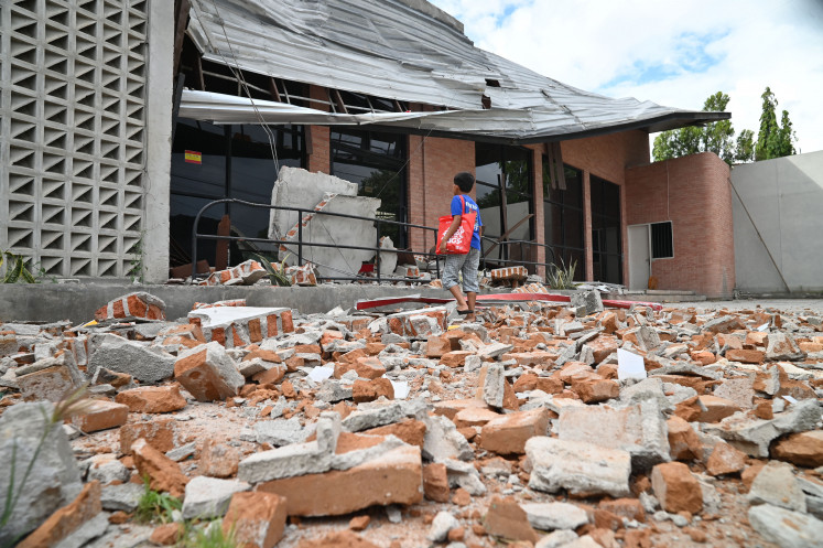 A child looks at a building damaged by a magnitude 6.7 earthquake on June 16 in Palu, Central Sulawesi. The earthquake killed one person, injured 76 others, triggered panic among residents and damaged a number of infrastructure facilities.